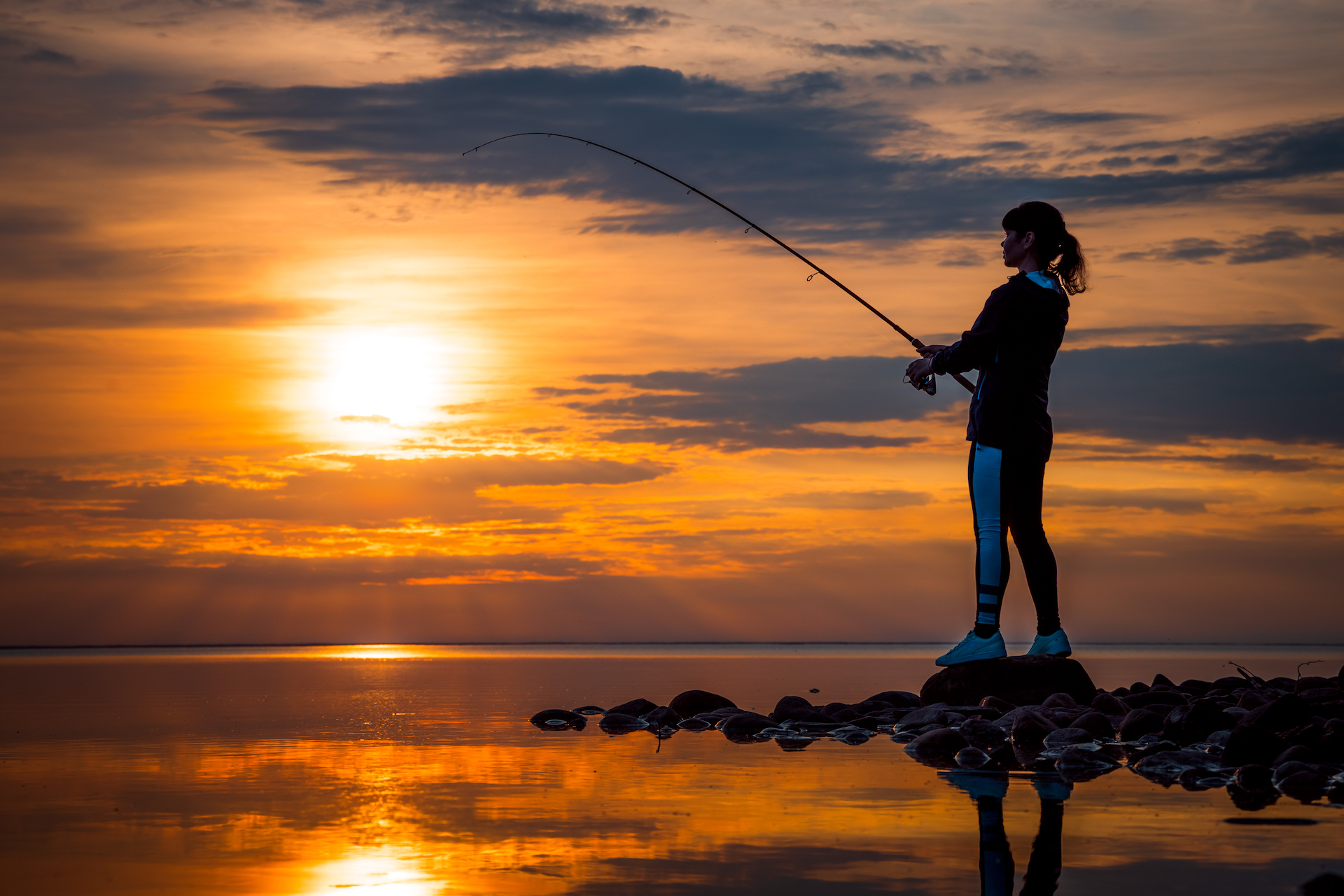 image of woman fishing at sunset from waterfront hotel