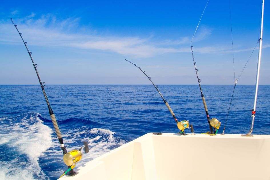 View from back of boat in the ocean with 3 deep-sea fishing rods