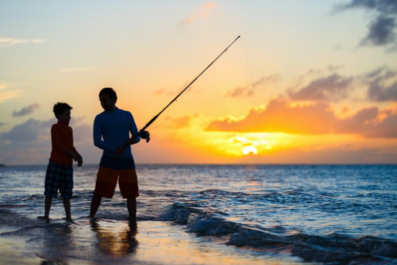2 boys fishing on the beach during sunset